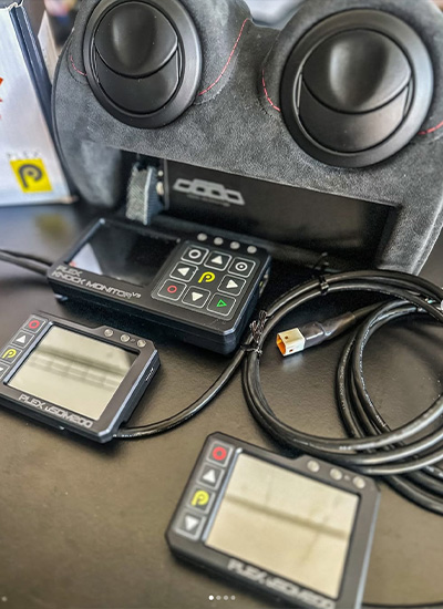 PLEX Knock Monitor V3 and two uSDM-200 Micro Displays placed in front of a custom Alcantara dashboard section for demonstration